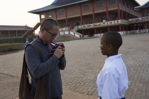 Acting Director, KC Tan adjusts a tie for student Lindokuhle Dludlu before breakfast at Amitofo Care Centre, Swaziland. Dludlu is in high school, the centre deosn't have a high school up and running as yet, so the students head to a local school by bus every morning at around 6:30am. Once back from school they catch up on their Chinese Mandarin language studies as well as other homework. Tan, originally from Singapore was at a Buddhist class and was told about Amitofo and wanted to volunteer. He got in touch with them and is now one of the directors at the Swaziland centre. CORNELL TUKIRI © 03 March 2017
